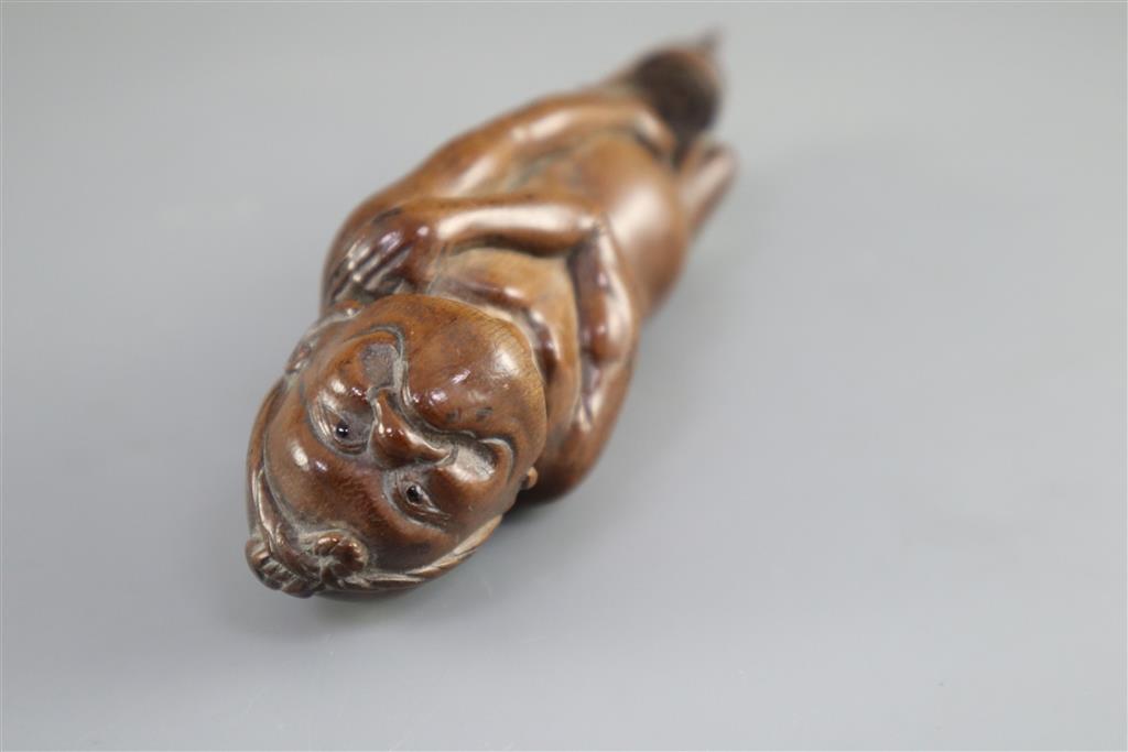 A Japanese cherrywood okimono netsuke of a farmer, early 19th century, 15cm long